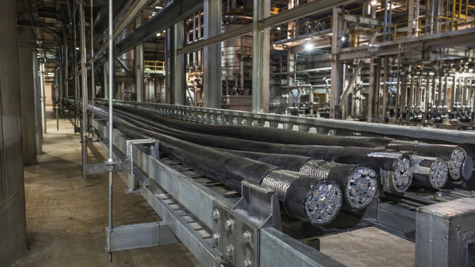 Large-diameter steel wire armored cables on a cable tray inside an industrial plant, showing weight and bulk challenges