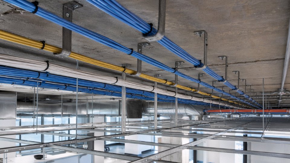 Low voltage Cat6 network cables supported on J-hooks above a suspended ceiling grid in a commercial office